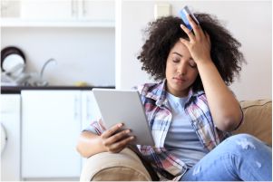 Young woman on couch frustrated with paying bills
